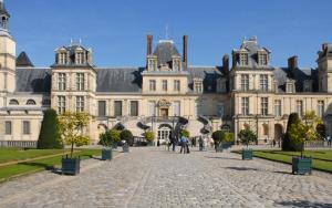 a large building with people walking in front of it at FORET DE FONTAINEBLEAU, chambre entrée privée. in Arbonne-la-Foret