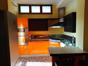 La cuisine est équipée d'armoires orange et d'un four avec plaques de cuisson. dans l'établissement Residence Taverna, à Plaisance