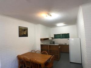 
a kitchen with a table and a refrigerator at Allan Cunningham Motel in Toowoomba
