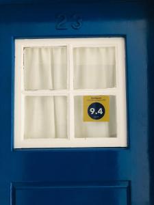 een blauwe deur met een raam met een bord erop bij Sea & Beach Apartment in Costa da Caparica