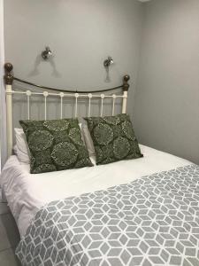 uma cama com lençóis e almofadas verdes e brancos em 5 on Pieter Hugo em Paarl