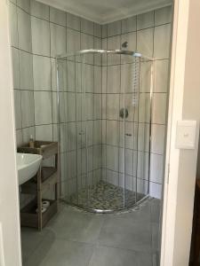a shower with a glass door next to a sink at 5 on Pieter Hugo in Paarl
