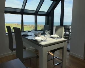 ein Esszimmer mit einem Tisch mit Stühlen und Fenstern in der Unterkunft Meermomente in Helgoland