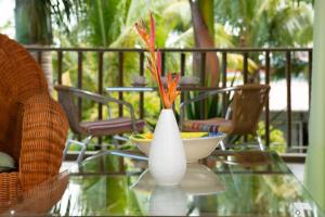 a glass table with a white vase with flowers in it at Rusty Pelican Heavenly Apt in La Gaulette