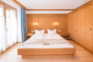 Schlafzimmer mit einem großen Bett und Holzwänden in der Unterkunft Das GÄSTEHAUS SCHNEIDER am Dorfplatz in Alpbach