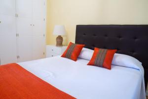 a bedroom with a large white bed with orange pillows at Apartamentos Duque Ventas in Madrid