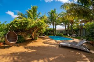 a backyard with a swimming pool and palm trees at Rusty Pelican Heavenly Apt in La Gaulette