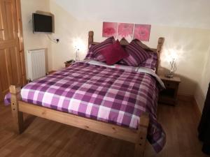 a bed with a purple and white checkered blanket at Melrose in Fort William
