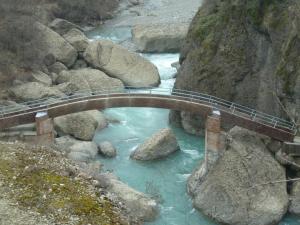 a wooden bridge over a river with rocks at Ciuchi House in Cantalupo Ligure