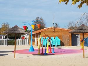 a playground with colorful play equipment in front of a building at Les Mathes in Les Mathes
