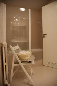 a white chair in a bathroom with a bath tub at Casa Andrea in Pamplona
