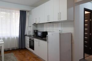 a kitchen with white cabinets and a refrigerator at Apartament Luca in Turda