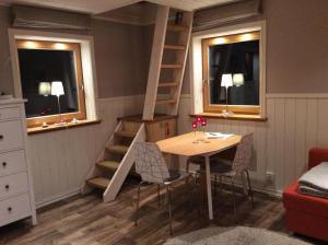 a room with a table and a ladder next to two windows at Mysig och modern Stuga på Snögård, nära havet och naturen in Lur