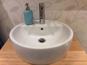 a white bathroom sink with a soap dispenser on it at Mysig och modern Stuga på Snögård, nära havet och naturen in Lur +24 photos
