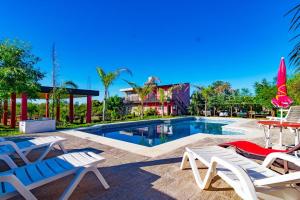 圣何塞HM San Jose的一个带椅子和桌子的游泳池以及一座房子