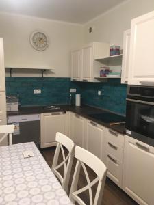 a kitchen with white cabinets and a table and a clock at Villa Casa Mia in Balatonlelle