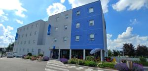 un gran edificio azul con flores en un estacionamiento en Ibis Budget Chalon Sur Saone Nord, en Chalon-sur-Saône