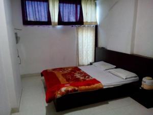 a bedroom with a bed with a red blanket and a window at Hotel Hari darshan in Nāthdwāra