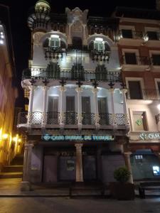 Un grand bâtiment blanc avec balcon est disponible la nuit. dans l'établissement Apartamento La Muralla de Teruel, à Teruel