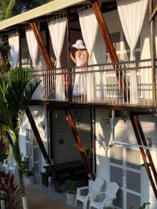 a woman standing on the balcony of a house at Hotel Ballena Dorada in Uvita
