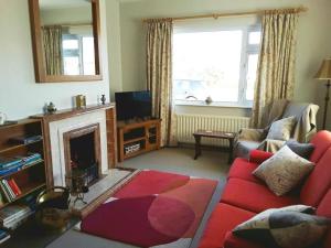 Kinard في Lisbellaw: غرفة معيشة مع أريكة حمراء ومدفأة