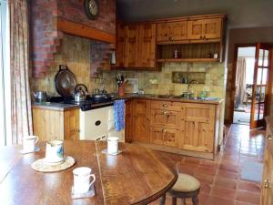 cocina con armarios de madera y mesa de madera en Kinard en Lisbellaw