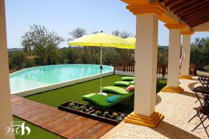 a patio with chairs and an umbrella and a pool at Monte do Mato dos Homens in Vidigueira