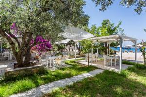 einen Garten mit Tischen und Stühlen unter einem Baum in der Unterkunft Limnonari double room in Skopelos