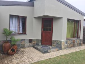 a house with a red door and two windows at Glentana Silver Moon Self Catering in Glentana