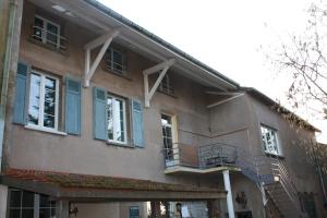 un edificio con finestre blu e balcone di Les 2 Granges Gîte a Bérig-Vintrange