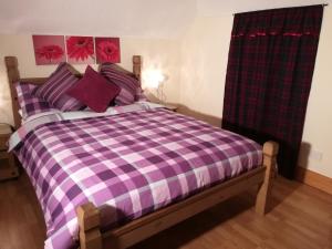 1 cama con manta a cuadros morada y blanca en Melrose en Fort William