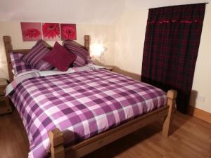 フォート・ウィリアムにあるMelroseの紫と白のチェック毛布付きのベッド