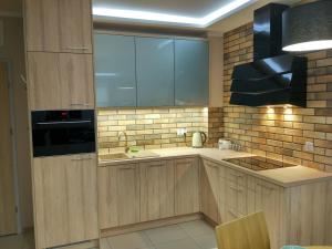eine Küche mit Holzschränken, einer Spüle und einer Mikrowelle in der Unterkunft Apartament Zielono Mi in Kołobrzeg