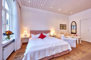 a bedroom with a large white bed and a couch at Hotel Föhrenhof Garni in Farchant