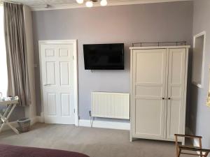 Habitación con armario blanco y TV en la pared. en The Monarch en Lytham St Annes