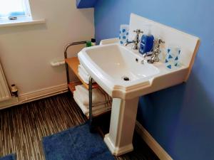 ein Badezimmer mit einem weißen Waschbecken an einer blauen Wand in der Unterkunft Schofield Guest House in Bridlington + 54 Fotos