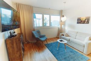 sala de estar con sofá blanco y silla azul en BestVienna U1 Kagran/DZ, en Viena