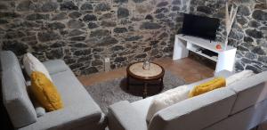 a living room with two couches and a tv at Casa Franco in Ponta do Pargo