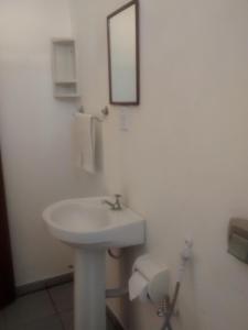 uma casa de banho branca com um lavatório e um espelho em Pousada Do Caju em Nova Viçosa