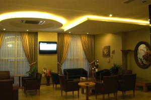 a waiting room with chairs and tables and a tv at Pınar Elite Hotel in Adana