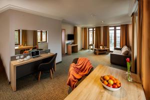 um quarto de hotel com uma sala de estar com uma mesa em Akacja Medical Resort em Ciechocinek