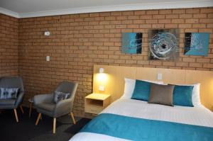 
a hotel room with a bed, chair and a lamp at Sunray Motor Inn in Toowoomba
