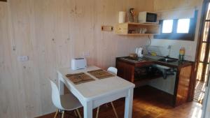a small kitchen with a white table and a sink at Lotus Lodge in Pichilemu