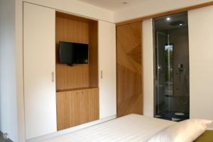 1 dormitorio con 1 cama y TV en la pared en Punta Bianca Suite & Home Experience, en Agrigento