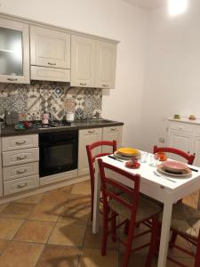 une cuisine avec une table blanche avec des chaises et une cuisinière dans l'établissement Casa della Nonna, à San Giovanni Suergiu