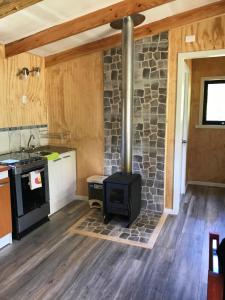 a kitchen with a stove and a stone wall at Rincón del Gaucho in Hornopiren