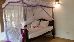 una camera da letto con letto a baldacchino con tende bianche di Lonely Beach Resort Tangalle a Tangalle