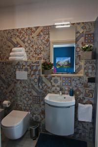 bagno con lavandino, servizi igienici e specchio di B&B Arco Caputi a Ruvo di Puglia