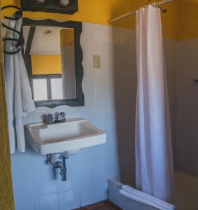 a bathroom with a sink and a shower curtain at Hotel Toliman in San Lucas Tolimán