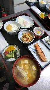 una mesa cubierta con platos de comida y tazones de sopa en Minshuku Yurika, en Urugi